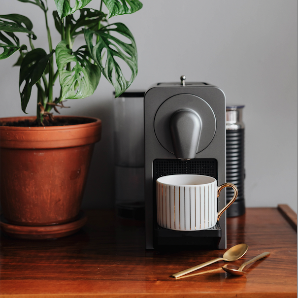 Nespresso coffee machine with gold table spoon and potted plant